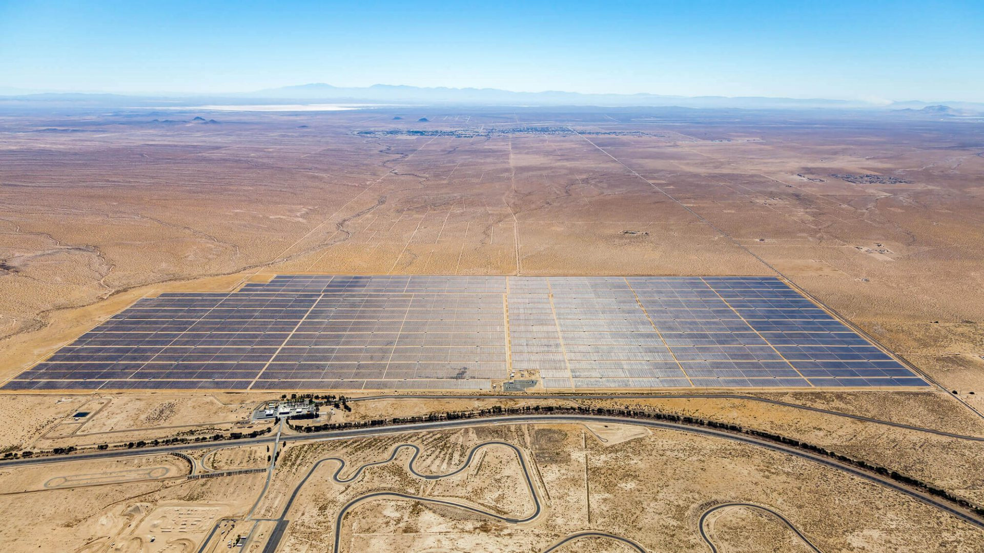 Desert aerial drone view of Springbok solar farm between a racetrack & mountains in California.